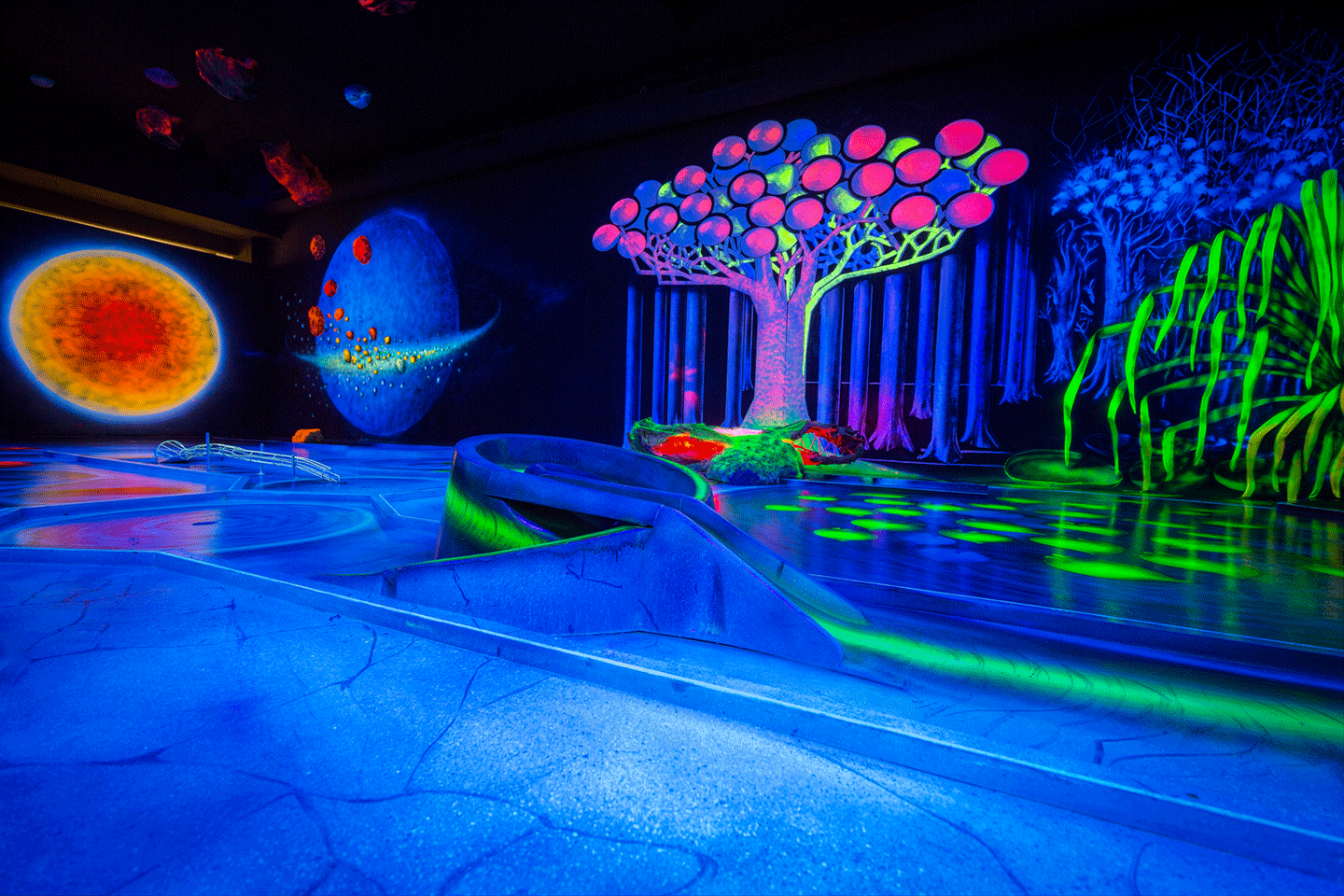 Leuchtende Schwarzlicht-Minigolfbahn mit farbigen Bäumen